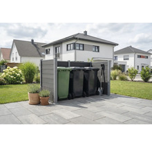 Moderne graue Mülltonnenverkleidung aus Verbundwerkstoff auf einer Terrasse in einem organisierten Garten mit Wohnhäusern im Hintergrund.