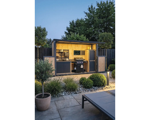 Moderne Außenküche im Garten mit Gasgrill, Holzverkleidung und Beleuchtung. Gut organisierter Grillplatz auf einer gepflasterten Steinterrasse.