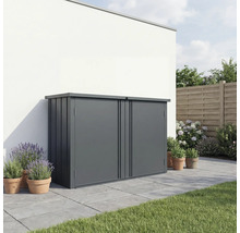Moderne Gartenbox aus Metall in Dunkelgrau auf einer gepflasterten Terrasse vor einer weißen Wand, umgeben von Pflanzen in Tontöpfen.