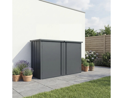 Moderne Gartenbox aus Metall in Dunkelgrau auf einer gepflasterten Terrasse vor einer weißen Wand, umgeben von Pflanzen in Tontöpfen.