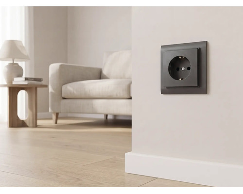 Dunkle Steckdose an einer hellen Wand in einem modern eingerichteten Wohnzimmer mit Sofa und Parkettboden.