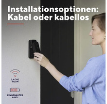 Frau montiert eine schwarze Videotürklingel an einer Wand. Text beschreibt Installationsoptionen mit Kabel oder kabellos mit eingebautem Akkumulator.