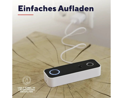 Smarte Türklingel wird über ein USB-C-Kabel an einer Steckdose aufgeladen. Das Gerät liegt auf einer Holzoberfläche.