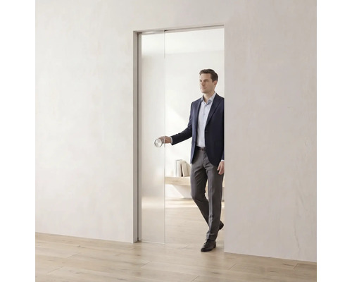 Glasschiebetür in einem hellen, minimalistischen Raum mit einer Person, die den runden Türgriff betätigt.