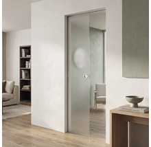 Moderne Glasschiebetür aus Milchglas in einem hellen Wohnzimmer mit hellem Parkettboden und weißer Wand.