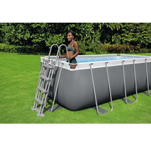Rechteckiger Aufstellpool mit grauem Rahmen und weißem Rand, inklusive Sicherheitsleiter, auf einer Rasenfläche im Garten.