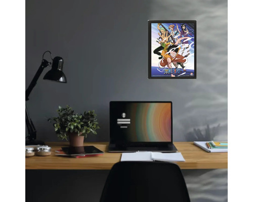 Gerahmtes One Piece Poster an einer Wand über einem Schreibtisch mit Laptop und Zimmerpflanze.