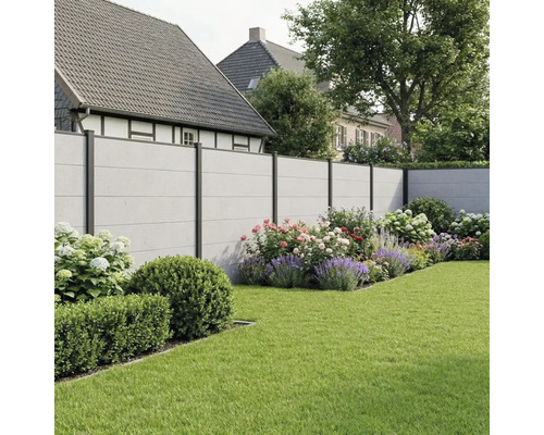 Moderner Sichtschutzzaun in Betonoptik mit dunklen Metallpfosten in einem Garten mit Blumenbeeten und Rasenfläche.