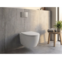Wand-WC in einem modernen Badezimmer mit Betonoptik, Drückerplatte an der Wand und einem Holzhocker mit Handtüchern und Pflanze.