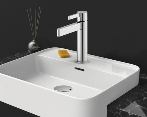 Moderne Einhebel-Waschtischarmatur in Chrom auf einem weißen Keramik-Waschbecken mit Seife auf einer Marmoroberfläche.
