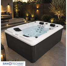 Rechteckiger Whirlpool mit weißer Wanne und dunkler Verkleidung auf einer beleuchteten Terrasse. Sanotechnik International Logo.