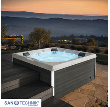 Quadratischer Outdoor Whirlpool von Sanotechnik mit dunkelgrauer Verkleidung in Holzoptik, LED Beleuchtung und Kopfstützen auf einer Terrasse.