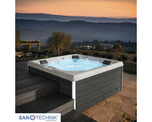 Quadratischer Outdoor Whirlpool von Sanotechnik mit dunkelgrauer Verkleidung in Holzoptik, LED Beleuchtung und Kopfstützen auf einer Terrasse.