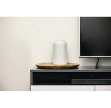 Hellbeige Vliestapete mit feiner Leinenstruktur in einem modernen Wohnzimmer hinter einem TV-Lowboard mit Dekoration.