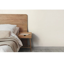 Helles Schlafzimmer mit Holzkopfteil, Nachttisch, weißem Bettzeug und hellbeiger Wandfarbe.