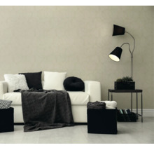Modernes Wohnzimmer mit gemusterter Tapete, weißem Sofa, schwarzen und weißen Kissen, einer dunklen Decke und einer zweiflammigen Stehlampe.