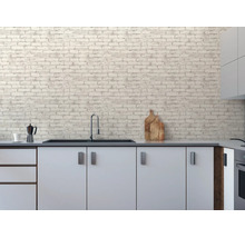 Moderne Küche mit weißen Schränken und Vliestapete in Ziegelsteinoptik an der Wand. Inklusive Spüle, Wasserhahn und Küchenzubehör.
