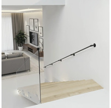 Schwarzer Handlauf aus Metall im Industrial-Stil an einer weißen Wand über einer Holztreppe mit Glasgeländer in einem modernen Wohnzimmer.