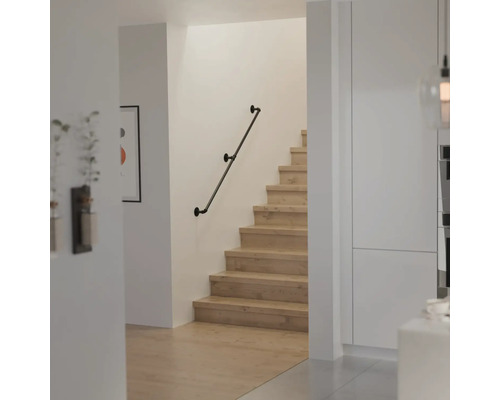 Moderner Treppenaufgang mit Holzstufen und einem Wandhandlauf im Industriedesign aus Metallrohren.