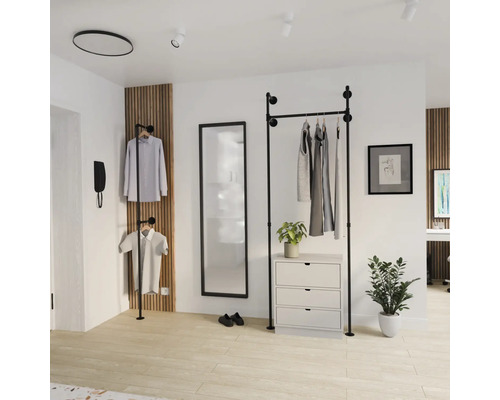 Offenes Garderobensystem aus schwarzen Rohren im Industrie-Design in einem hellen Raum mit Spiegel, Kommode und Holz-Wandpaneel.