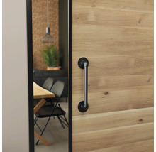 Schiebetür aus Holz mit schwarzem Stangengriff im Industrial-Design, Blick in ein Esszimmer mit Holztisch und schwarzen Stühlen.