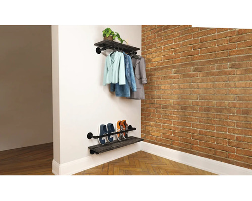 Wandgarderobe und Schuhregal im Industrial Style aus dunklem Holz und schwarzen Metallrohren mit aufgehängten Jacken und abgestellten Schuhen.