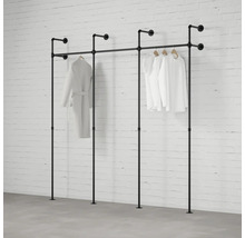 Industrielles Kleiderstangen-System aus schwarzen Metallrohren, Wand- und Bodenmontage, dreiteilig, mit hängender Kleidung vor einer Ziegelwand.