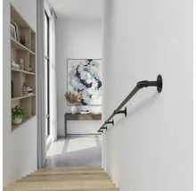 Schwarzer Handlauf aus Metall im Industrie-Design an einer weißen Wand in einem hellen, modernen Flur mit Holztreppe.