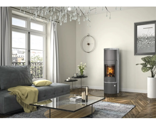 Moderner Kaminofen in einem hellen Wohnzimmer mit Parkettboden, Sofa und großem Kronleuchter.