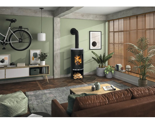 Moderner Kaminofen in einem hellen Wohnzimmer mit Parkettboden, Ledersofa und Zimmerpflanzen. Der Ofen brennt mit sichtbarem Holzfeuer.