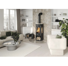 Moderner, heller Wohnraum mit schwarzem Kaminofen vor einer Steinwand, weißem Sofa, Sessel, grauem Couchtisch und weißen Regalen.