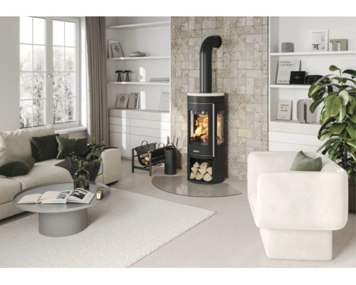 Moderner, heller Wohnraum mit schwarzem Kaminofen vor einer Steinwand, weißem Sofa, Sessel, grauem Couchtisch und weißen Regalen.