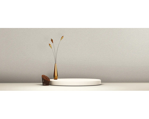 Strukturierte Wand mit rundem Podest, einer schlanken goldenen Vase mit drei dekorativen Zweigen und einem kleinen braunen geflochtenen Sessel.