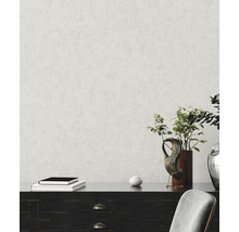 Vliestapete mit feiner Putzstruktur an einer Wand hinter einem dunklen Sideboard mit Dekoration und einer Pflanze.