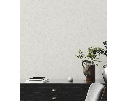 Vliestapete mit feiner Putzstruktur an einer Wand hinter einem dunklen Sideboard mit Dekoration und einer Pflanze.