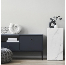 Modernes Wohnzimmer mit dunkelblauem Sideboard, grauem Strickpouf und einer Säule in Marmor-Optik vor einer hellen, strukturierten Wand.