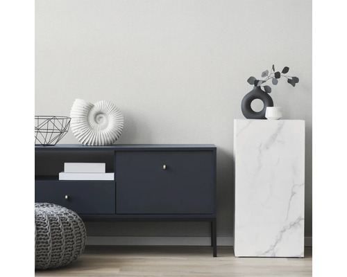 Modernes Wohnzimmer mit dunkelblauem Sideboard, grauem Strickpouf und einer Säule in Marmor-Optik vor einer hellen, strukturierten Wand.