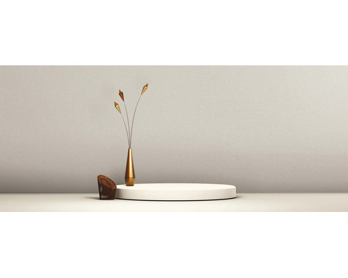 Minimalistische helle Szene mit weißem Podest, goldfarbener Vase mit dekorativen Zweigen und kleinem Korb vor einer strukturierten Wand.
