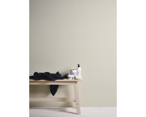 Innenwand in hellem Beigeton gestrichen, minimalistische Einrichtung mit Holzbank und Pflegeprodukten.