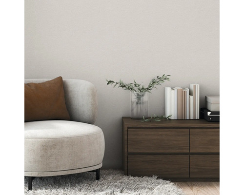 Modernes Wohnzimmer mit strukturierter Wandgestaltung, einem beigen Sessel mit braunem Kissen und einer dunklen Holzkommode.