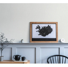 Holzbilderrahmen mit einer schwarz-weißen Island-Karte auf einer Wandleiste in einem hellen, minimalistischen Raum.