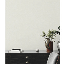 Strukturierte Vliestapete in Leinenoptik an einer Wand hinter einem dunklen Sideboard mit Dekoration und Büchern.