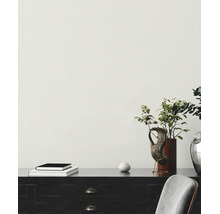 Heller Raum mit strukturierter Tapete, Sideboard mit Pflanzen, Büchern und Dekoration sowie einem Stuhl.