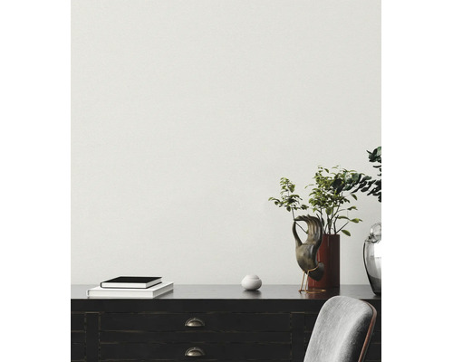 Heller Raum mit strukturierter Tapete, Sideboard mit Pflanzen, Büchern und Dekoration sowie einem Stuhl.