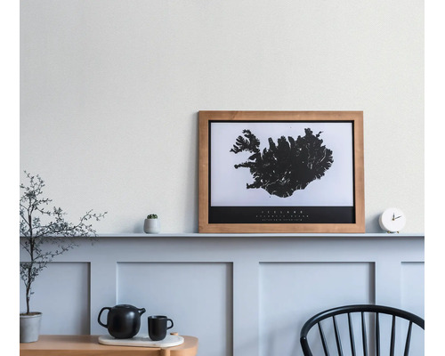 Gerahmtes Poster mit Island-Karte im Holzrahmen auf einem Regal in einem hellen, modern gestalteten Raum mit Wandpaneelen und Dekoration.