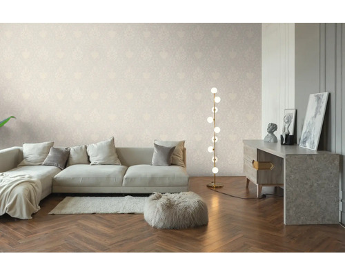 Helles Wohnzimmer mit dezent gemusterter Tapete, hellem Sofa, moderner Stehlampe und Parkettboden in Fischgrätoptik.