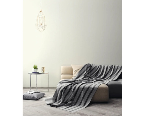 Helles Wohnzimmer mit cremefarbener Wand, Sofa mit gestreifter Decke, Beistelltisch und geometrischer Pendelleuchte auf Parkettboden.