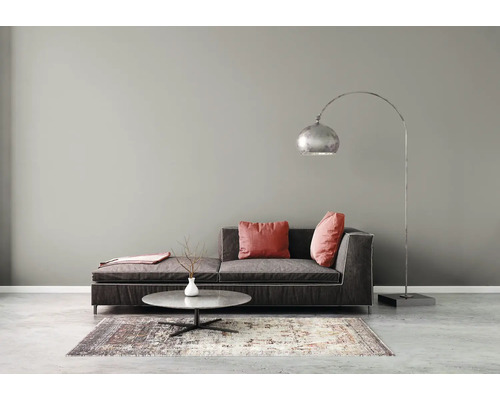 Modernes Wohnzimmer mit dunklem Stoffsofa, roten Kissen, rundem Marmor-Couchtisch, gemustertem Teppich und silberner Bogenstehleuchte.
