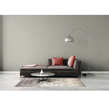 Modernes Wohnzimmer mit dunklem Sofa, Bogenstehleuchte, rundem Couchtisch und gemustertem Teppich vor einer grauen Wand.