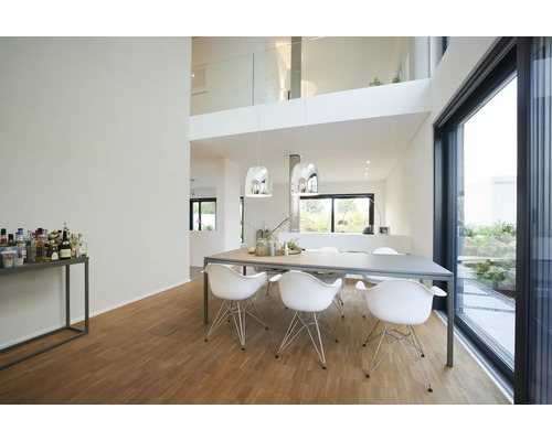 Modernes, helles Esszimmer mit großem Esstisch, weißen Designerstühlen, silbernen Pendelleuchten, Holzfußboden und bodentiefen Fenstern.